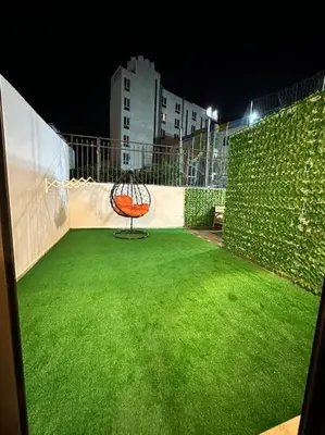 a green yard with a chair on top of it at Stylish Luxe Apartment F-R 0003 in Amman