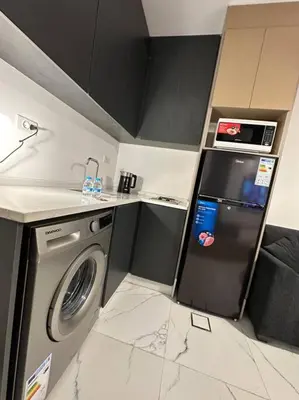 a small kitchen with a refrigerator and a washing machine at Stylish Luxe Apartment F-R 0003 in Amman