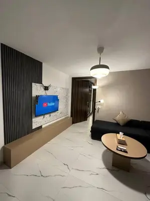 a living room with a couch and a tv on a wall at Stylish Luxe Apartment F-R 0006 in Amman