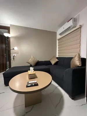 a living room with a black couch and a table at Stylish Luxe Apartment F-R 0006 in Amman