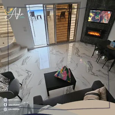 a living room with marble floors and a fireplace at Ayla Chalets in Amman