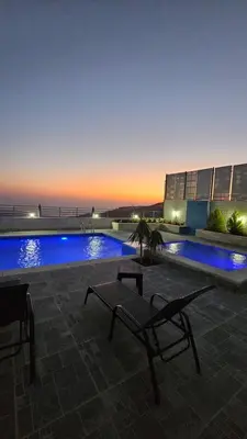 a swimming pool with a bench in front of a building at Ayla Chalets in Amman