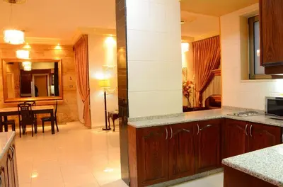 a kitchen with a counter and a dining room at Jad Hotel & Suite in Umm Uthainah