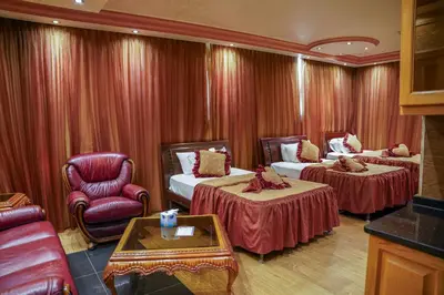 a hotel room with two beds and a chair at Jad Hotel & Suite in Umm Uthainah