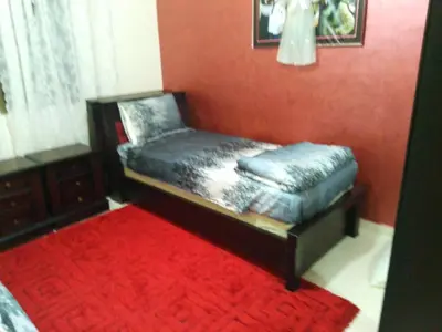 a small bed in a room with a red wall at Ayola Apartment in Madaba