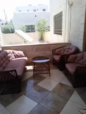 a room with two couches and a table and a window at Ayola Apartment in Madaba