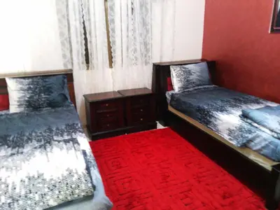 a bedroom with two beds and a red carpet at Ayola Apartment in Madaba