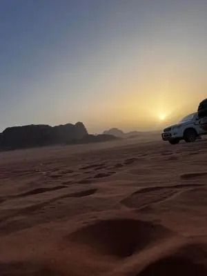 a truck parked in the desert with the sunset at Titanic Wadi Rum in Disah