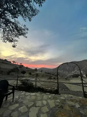 a person sitting on a bench watching the sunset at Dana horizon hotel in Dana