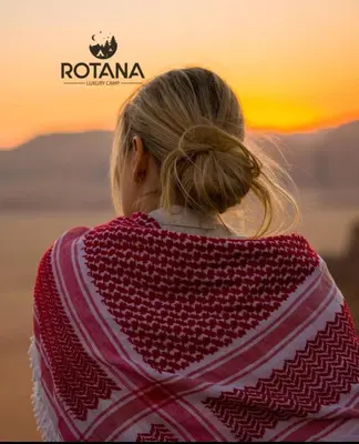 a woman wrapped in a scarf watching the sunset at Rotana luxury camp in Wadi Rum