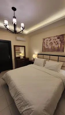 a bedroom with a large white bed and a chandelier at Residents Specialists in Amman