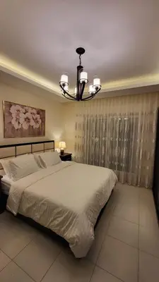 a bedroom with a large bed and a chandelier at Residents Specialists in Amman