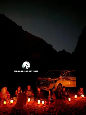 a group of people sitting in front of a car with candles at Diamond luxury rum in Wadi Rum