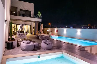 a swimming pool with chairs next to a building at The Gray Villas in Sowayma