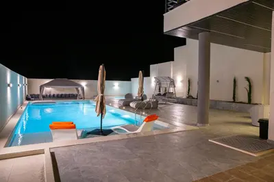 a swimming pool with chairs and umbrellas in a building at The Gray Villas in Sowayma
