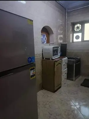a kitchen with a refrigerator and a computer on a counter at 3030 Inn in Irbid