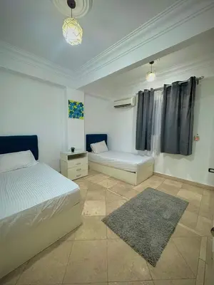 a white bedroom with two beds and a rug at Lotees House in Udhruḩ