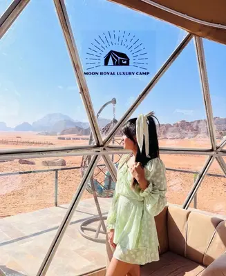 a woman in a green dress looking out at the desert at ROYAL MOON BUBBLES lUXURY CAMP in Wadi Rum