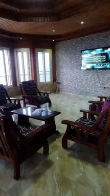 a living room with chairs and tables and a tv at Rest Inn in Kerak