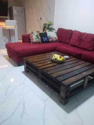 a living room with a red couch and a wooden coffee table at Bait Al-Masri in Um Qeis