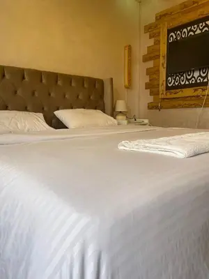 a bedroom with two beds with white sheets and a headboard at زهرة المدائن in Jerash