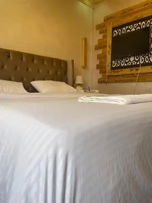 a bedroom with a large white bed with a tv on the wall at زهرة المدائن in Jerash