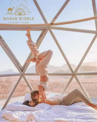 a man and a woman on a bed in a tent at Manar Bubbel Luxury Camp in Wadi Rum