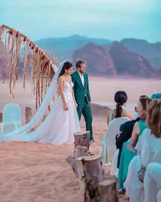 a bride and groom walking down the beach at MOON RUM lUXURY CAMP in Wadi Rum