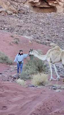 a man standing next to a camel in the desert at Um sabatah camp in Wadi Rum