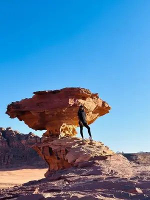 a man standing on a rock in the desert at Ram Al-Umda Luxury Camp in Wadi Rum