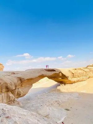 two people standing on a large rock on the beach at Ram Al-Umda Luxury Camp in Wadi Rum