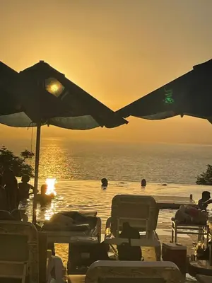 a beach with chairs and umbrellas and people in the water at The F52 Luxury Residence Samarah Resort in Sowayma