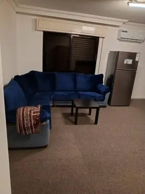 a living room with a blue couch and a table at Kamalia Studio in Şāfūţ