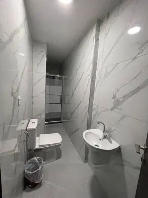a white bathroom with a toilet and a sink at شقارى 13 in Ţāb Kirā‘
