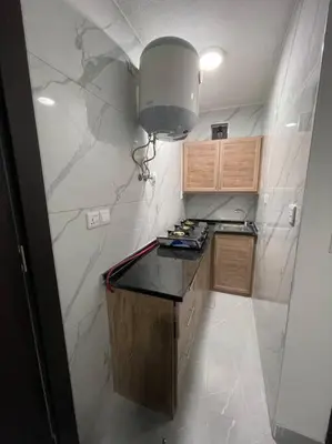 a small kitchen with a black counter and a light at شقارى 14 in Ţāb Kirā‘