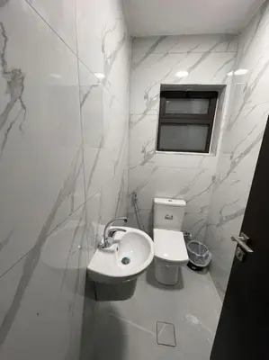 a white bathroom with a toilet and a sink at شقارى 10 in Ţāb Kirā‘