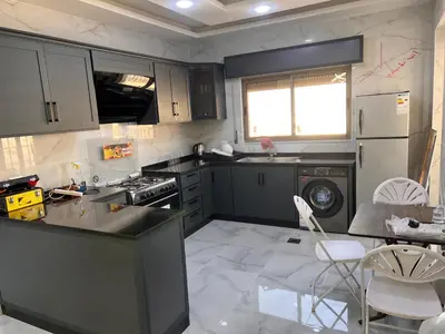 a kitchen with black cabinets and white appliances at شقة مفروشة و جديدة مع كراج للسيارة في ارقى مناطق اربد in Irbid