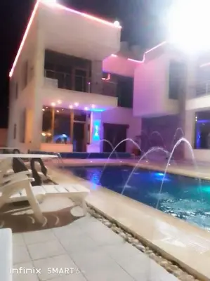 a swimming pool in front of a building at night at Vienna Villa for you in Al Qasţal