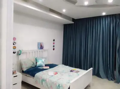 a bedroom with a bed and a blue curtain at Vienna Villa for you in Al Qasţal