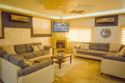 a living room with two couches and a tv at Tallet falastin in Umm Juraysāt