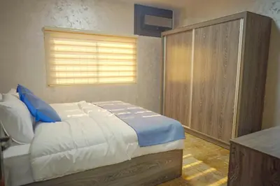 a bedroom with a bed and a wooden cabinet at Tallet falastin in Umm Juraysāt