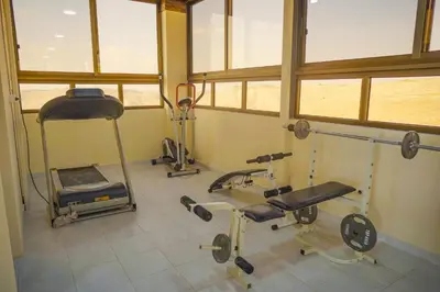 a gym with several exercise equipment in a room with windows at Tallet falastin in Umm Juraysāt