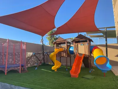 a playground with a slide and swings at Tallet falastin in Umm Juraysāt