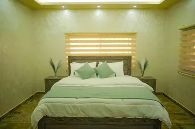 a bedroom with a large bed with green sheets and pillows at Tallet falastin in Umm Juraysāt