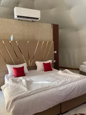 a large white bed with two red pillows on it at Rum Rosella camp in Wadi Rum