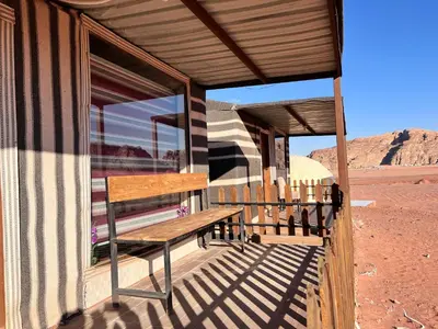 a wooden bench on the porch of a building in the desert at Rum Ronaldo camp in Wadi Rum