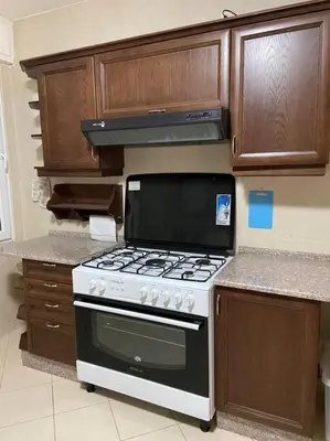 a kitchen with a stove and wooden cabinets at Apartment in Amman Khalda in Amman