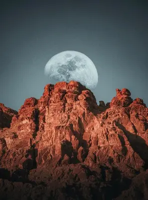 a moon rising over the top of a mountain at RUM YANAL lUXURY CAMP in Wadi Rum