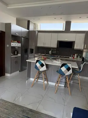 a kitchen with two bar stools and a counter at Modern Rooftop apartment in Amman