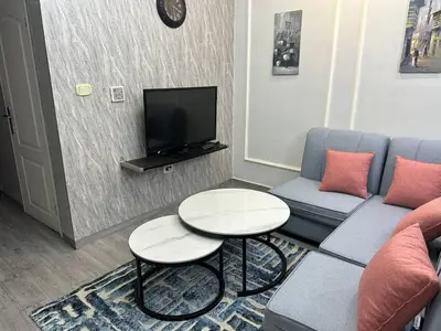 a living room with a couch and tables and a tv at استوديو مفروش لشخصين الجاردنز 320 in Amman